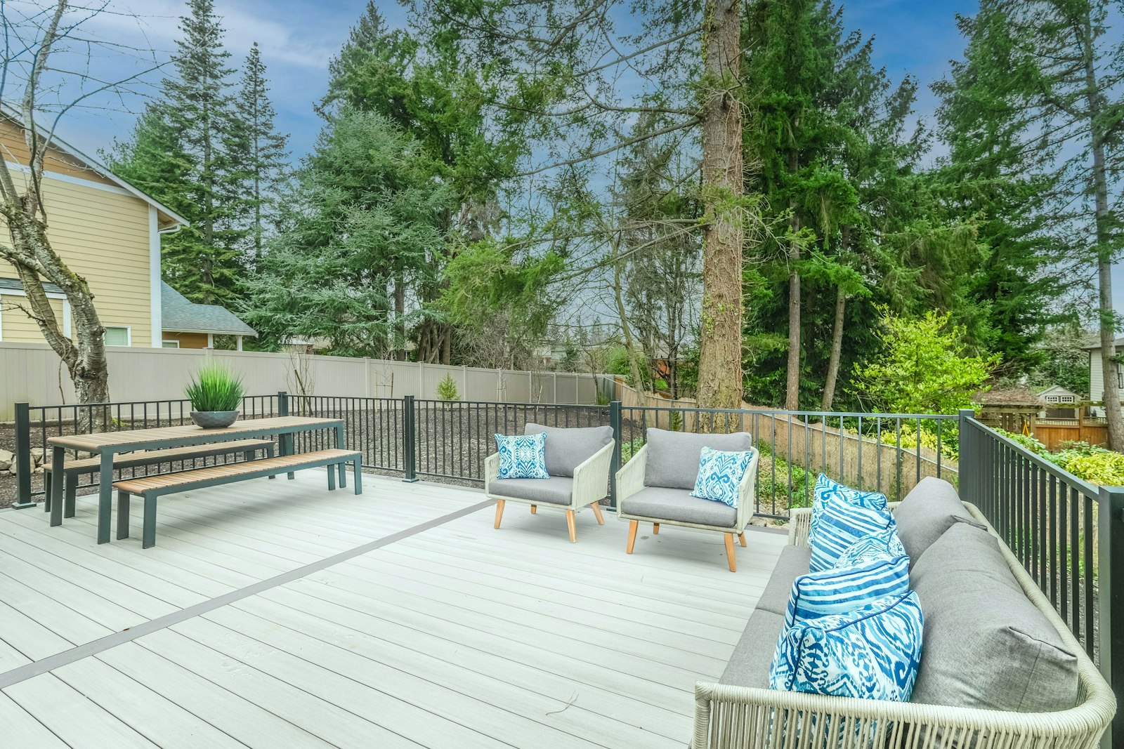 A spacious composite deck with seating and a dining set, bordered by black railing.